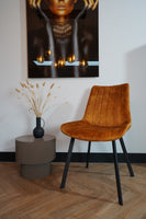 Modern living room featuring Eetkamerstoel Marilene velvet chair with unique design, next to a minimalist side table and wall art.